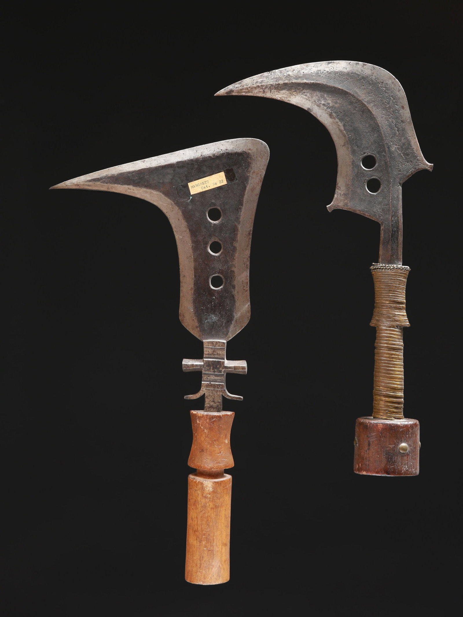 2 Mangbetu Ceremonial Knives, "trumbash/emambele": 2 Zeremonial-Messer, "trumbash/emambele" Mangbetu. DR Kongo Ohne Sockel / without base Holz, Eisen, Kupferlegierung, Polsternägel. H 39 - 42 cm. Provenienz: - lt. Charles Indlekofer: 1970er-Jahre
