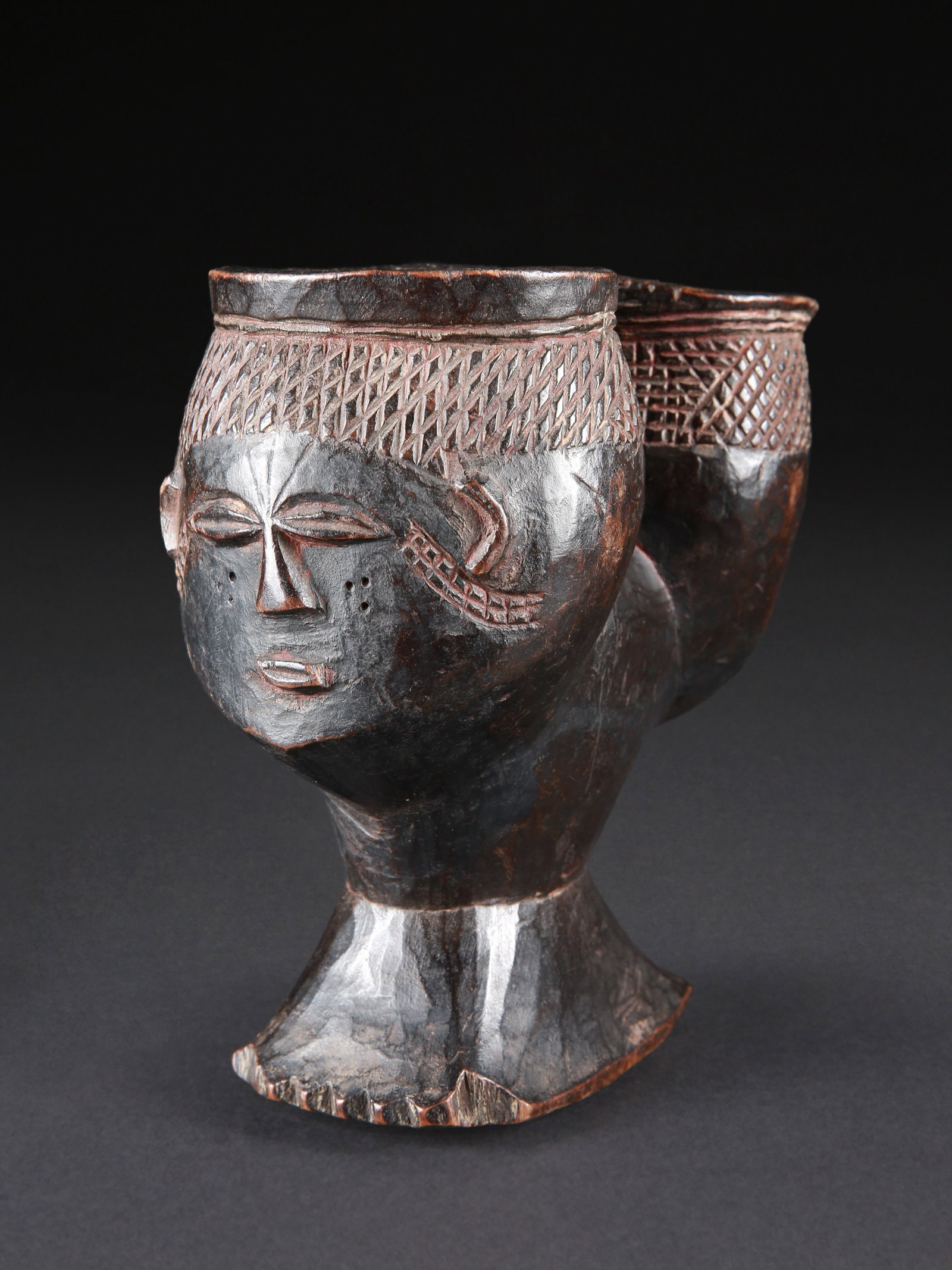 A Wongo janiform double Palm Wine Cup: Janusförmiger Palmwein-Doppelbecher Wongo. DR Kongo Ohne Sockel / without base Holz. H 15 cm. Provenienz: - Witold Grünbaum (1921-2007), Chez-le-Bart. - Hôtel des Ventes SA, Genf, 09.03