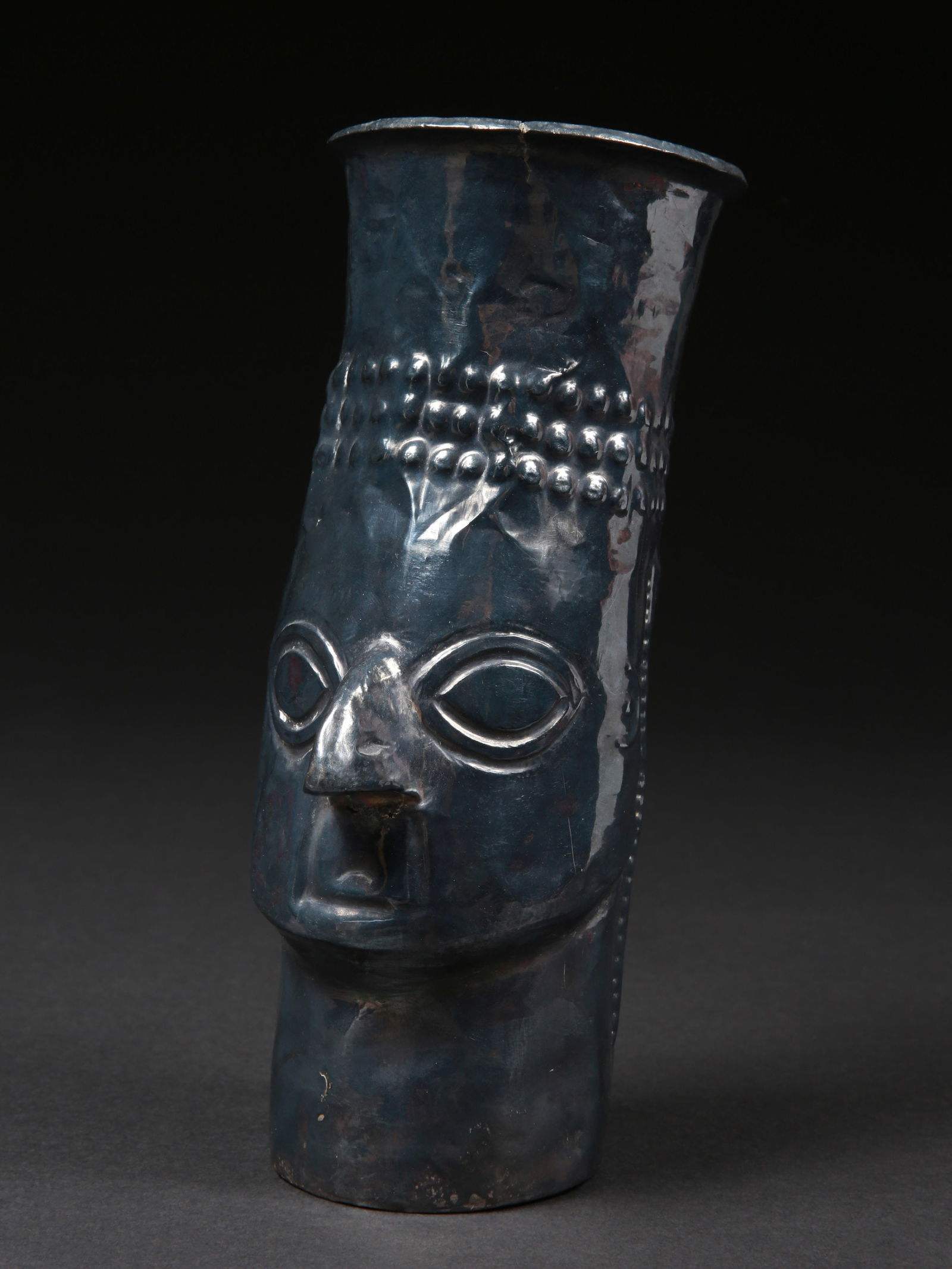 A Sicán Silver Effigy Beaker, "Kero": Zeremonialbecher in Form eines Kopfes, "Kero" Sicán. Peru Ohne Sockel / without base Silber. H 23 cm. Provenienz: - amerikanische Privatsammlung, Los Angeles. - Schweizer Privatsammlung, Genf. CHF 2