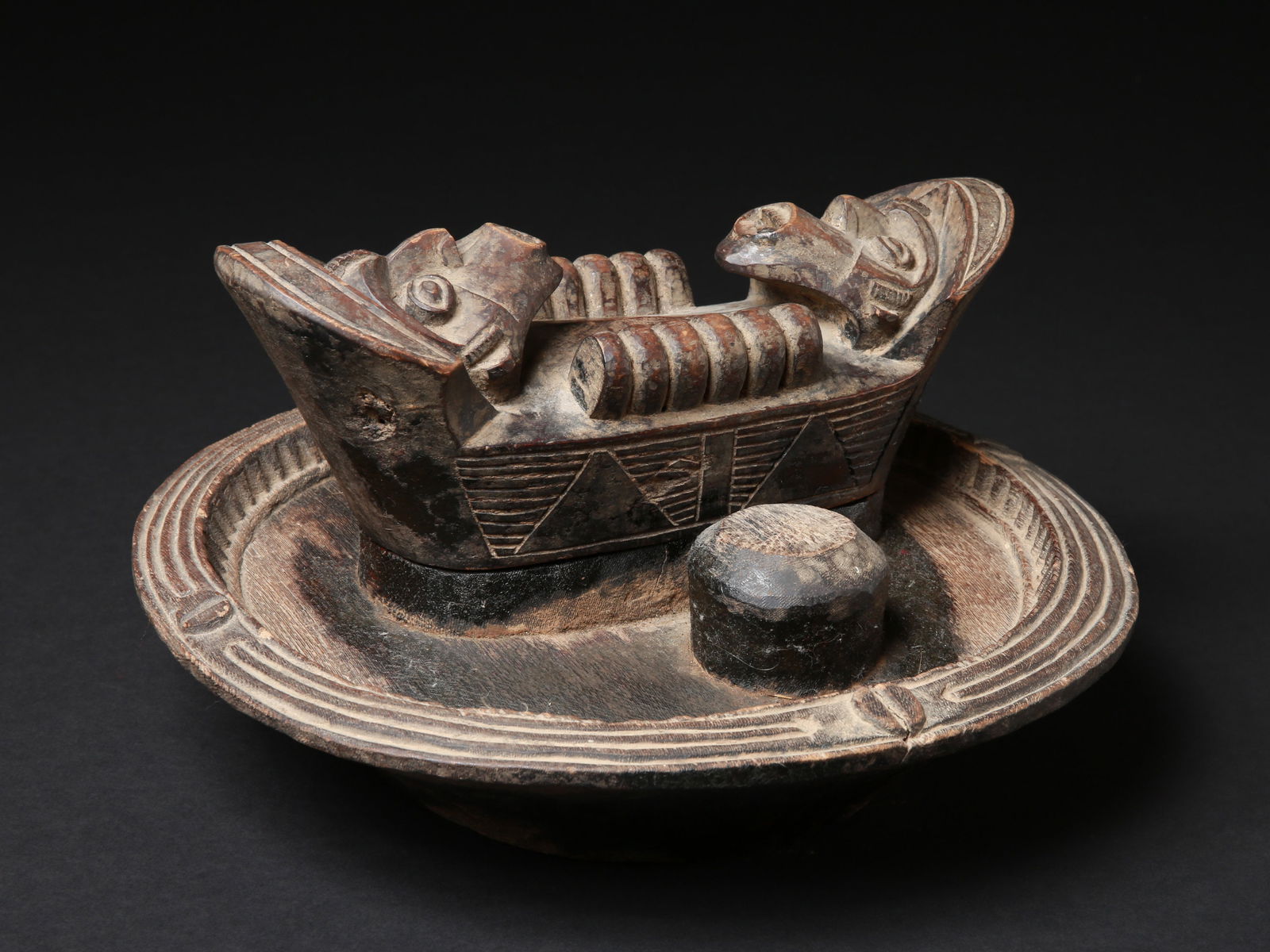 An Igbo Container for Kola Nuts, "okwa oji": Reich verzierter Kolanuss Behälter, "okwa oji" Igbo. Nigeria Ohne Sockel / without base Holz. H 17,5 cm. L 30.5 cm. Ø 31 cm. Provenienz: - Alfred Spinnler (1940-2023), Wittingsburg. - Bentle