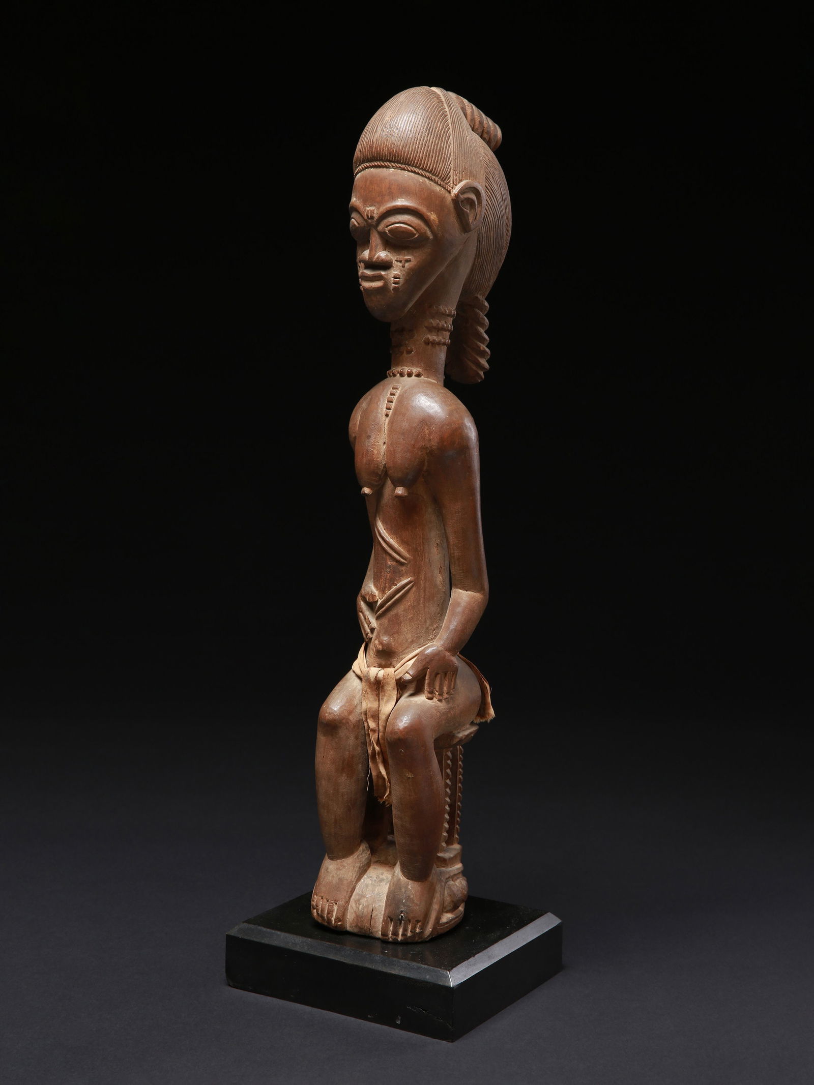 A Baule seated Figure: Sitzende weibliche Figur Baule. Côte d’Ivoire Mit Sockel / with base Holz, Textil. H 50 cm. Provenienz: - Josef Müller (1887-1977), Solothurn. - Monique und Jean Paul Barbier-Mueller,