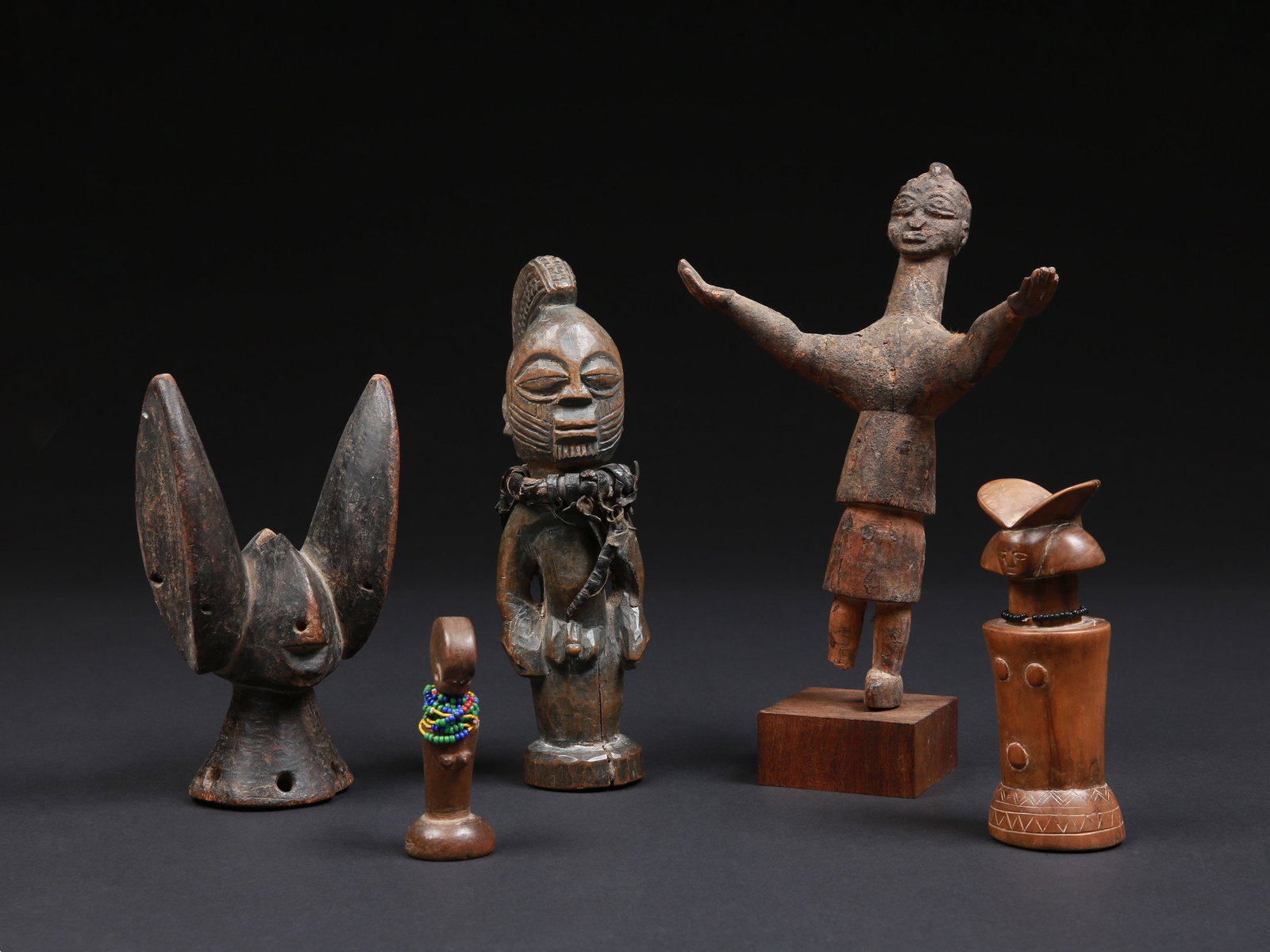 4 Figures and a Headdress: 4 Figuren und ein Kopfaufsatz Bamana / Zaramo / Yoruba / Lobi / Kwere. Mali, Burkina Faso, Nigeria, Tansania Mit einem Sockel / with one base Holz, Glasperlen. H 8,5 - 25,5 cm. Provenienz: -