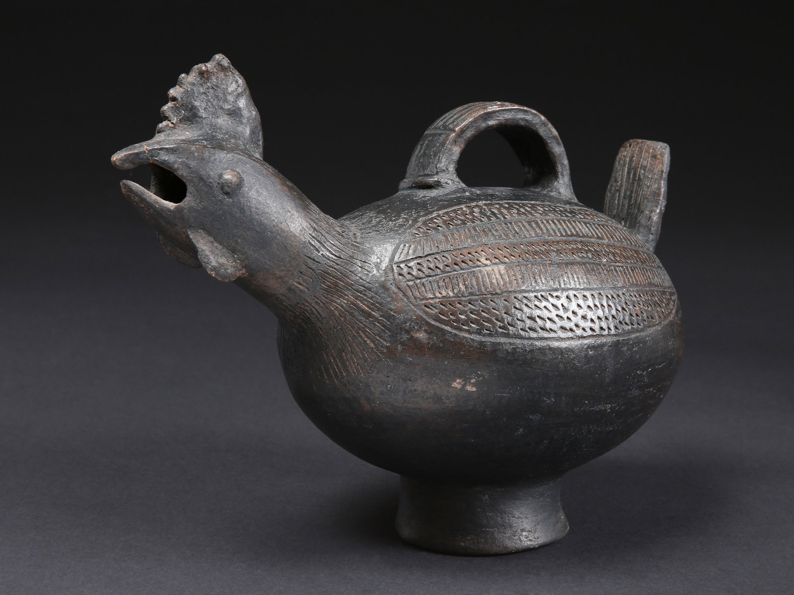 A Baule Vessel in the Shape of a Bird with Handle: Terrakotta-Gefäss mit Ausguss und Henkel in Form eines Vogels Baule. Côte d’Ivoire, Toumodi Departement Ohne Sockel / without base Terrakotta. H 21 cm. L 28 cm. Provenienz: