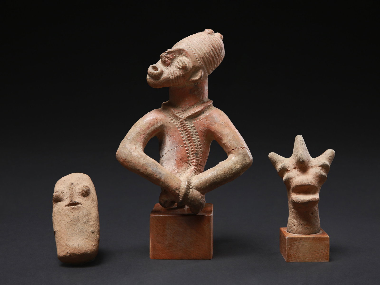 A Djenne Half-Figure and two Eotilé Heads, "asumkutua": Djenne Halbfigur und zwei Eotilé-Köpfe, "asumkutua" Sao / Djenne / Eotilé (Bétibé, Mekyibo). Tschad / Mali / Côte d'Ivoire Mit 2 Sockeln / with 2 bases Terrakotta. H 8 -
