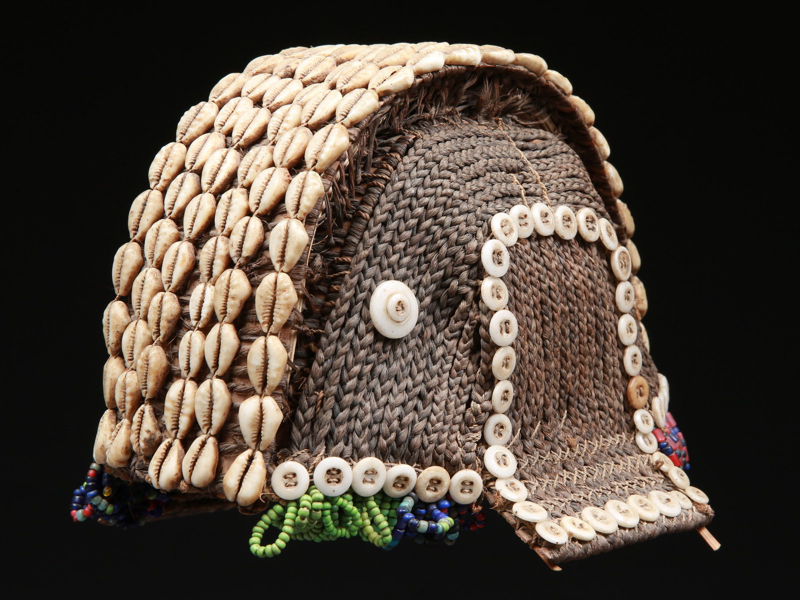 A Fang wig-like Cap, "nlô-ô-ñgo": Perückenartige Kopfbedeckung, "nlô-ô-ñgo" Fang. Gabon Ohne Sockel / without base Pflanzenfasern, Kaurischnecken, Knöpfe, Glasperlen. H 13 cm. Provenienz: - Sammlung Haas,