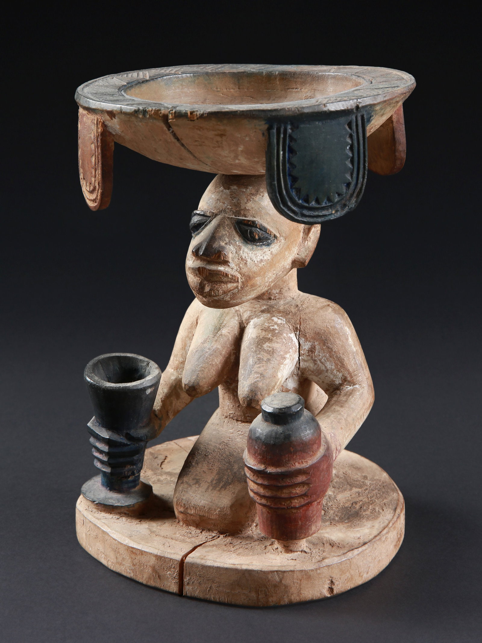 A Yoruba Divination Bowl with kneeling Woman, "agere ifa": Schalenträgerin, "agere ifa" Yoruba. Nigeria Ohne Sockel / without base Holz. H 22,5 cm. Provenienz: - Schweizer Privatsammlung, Zürich. - Hammer Auktionen, Basel, 18.02.2026, Lot 50. Storni