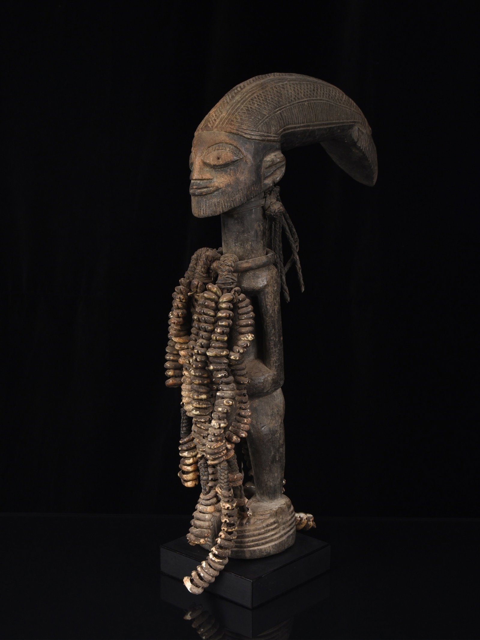 A Yoruba standing Figure from the Eshu Cult, "ogo elegba": Stehende männliche Figur aus dem Eshu Kult, "ogo elegba" Yoruba. Nigeria Mit Sockel / with base Holz, Eisen, Kaurischnecken. H 45 cm. L 26 cm. Provenienz: Galerie Walu, Zürich (vor 1999). Es
