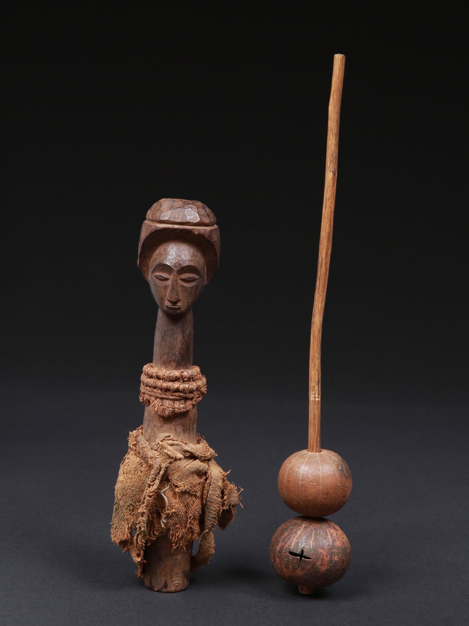A Luba Rattle with a Janus-shaped Handle, “minyange”: Rassel mit janusförmigem Griff, "minyange" Luba. DR Kongo Ohne Sockel / without base Holz, Textil, Schnur, Kalebasse. H 25 cm. Provenienz: Primus und Veronika Monn (1940-2006 / 1941-2025) Bern.