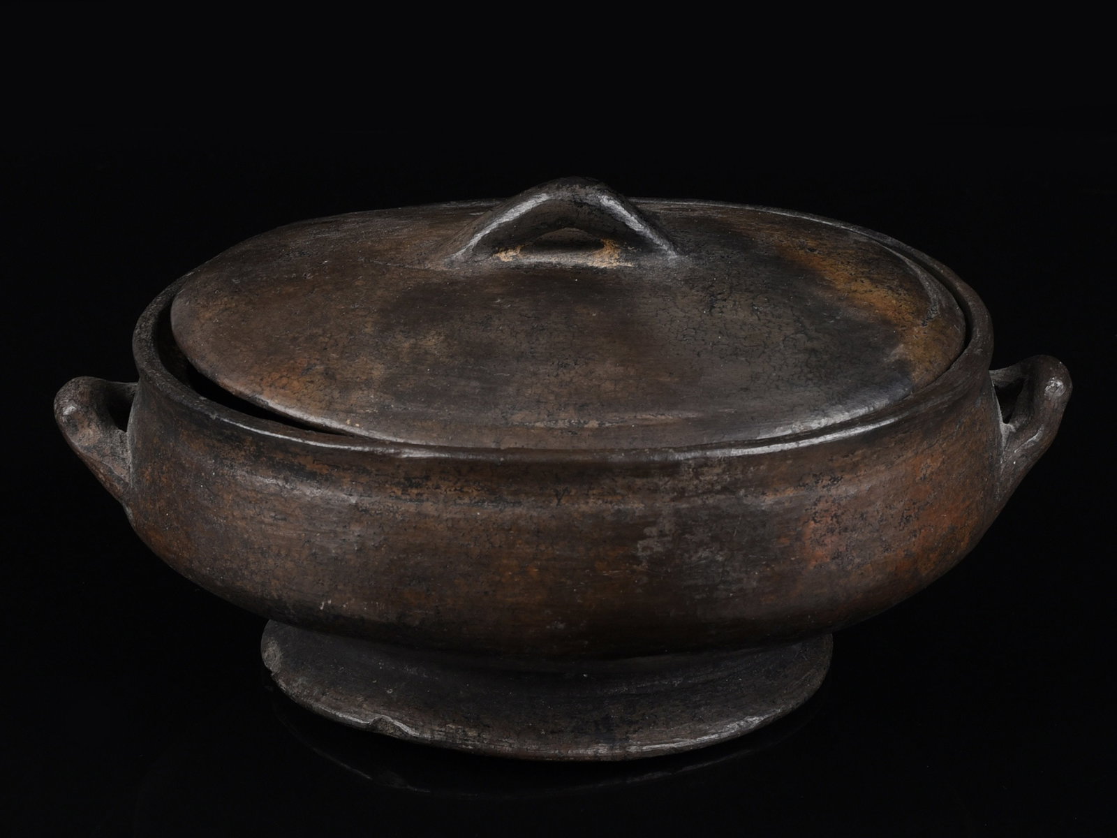 An Asante Bowl with two Side Handles and a Lid: Schale mit zwei seitlichen Griffen und einem Deckel Asante. Ghana Ohne Sockel / without base Terrakotta. H 9,5 cm. Ø 17 cm. Provenienz: - Brigitte Menzel (1930-1998), Berlin. - Erbengemeinschaft