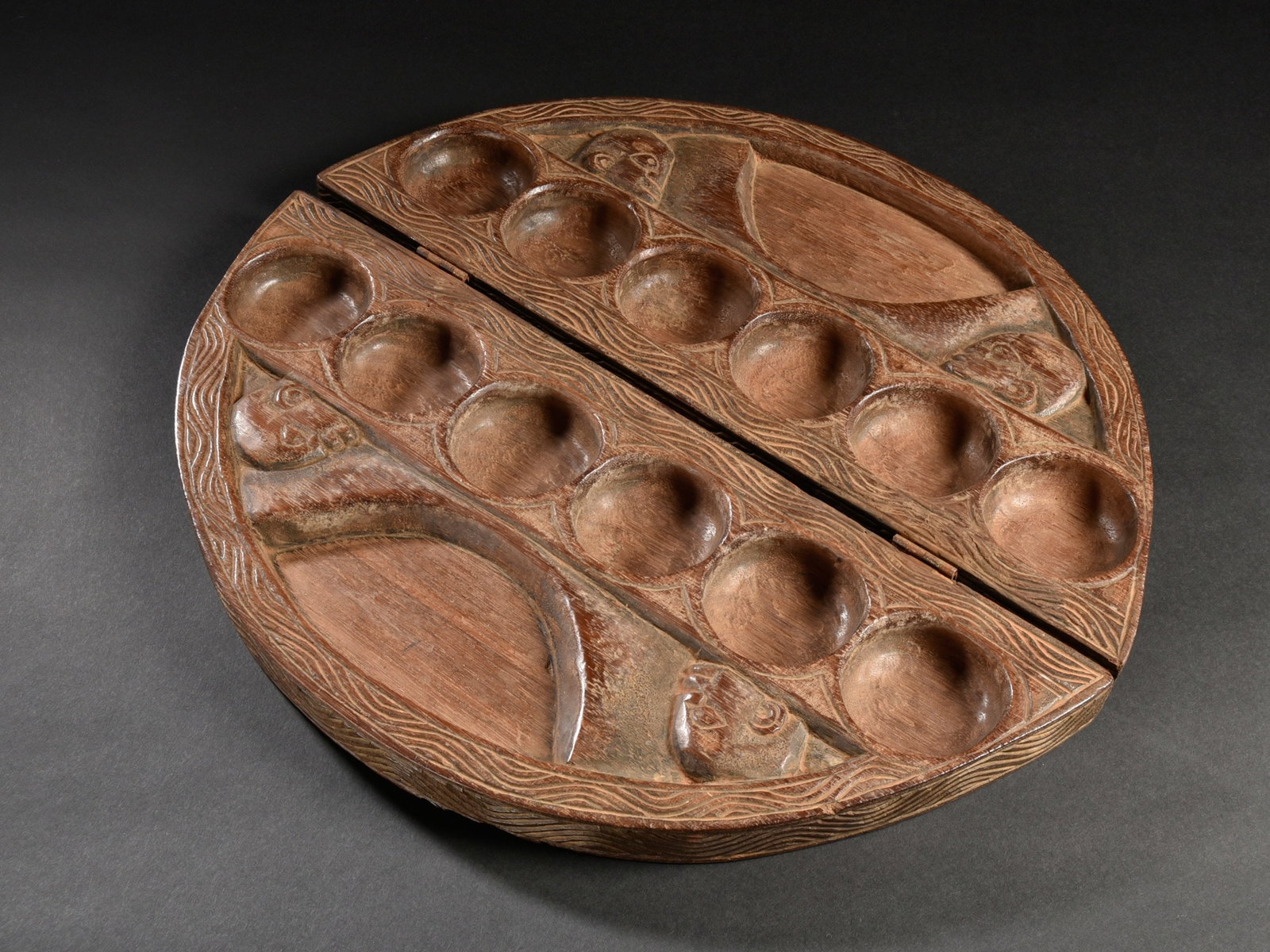 A Foldable Gameboard, "ayoayo": Faltbares Spielbrett, "ayoayo" Edo. Nigeria Ohne Sockel / without base Holz. Ø 48,5 cm. Provenienz: - Galerie Walu, Zürich. - Ernest Risch (1927-2015), Oberwil. - Hammer Auktionen, Basel,