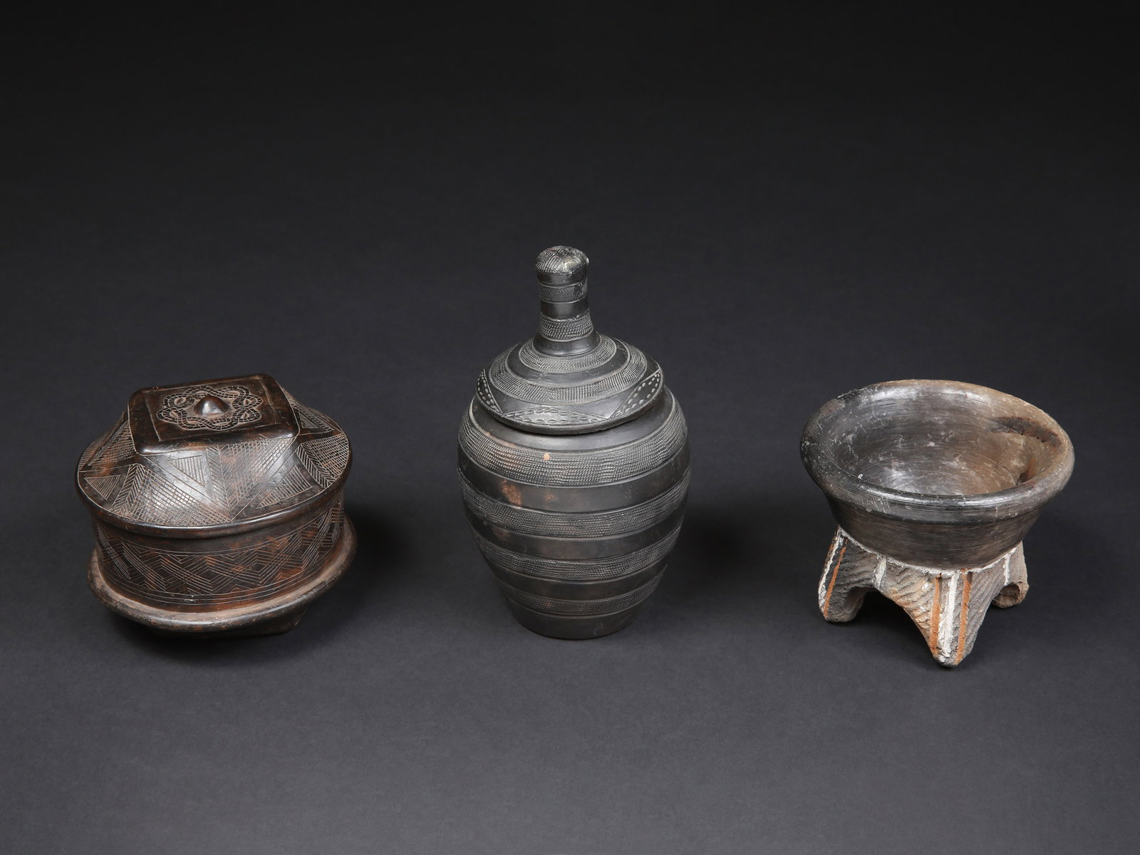 2 lidded Containers and a Bowl: 2 Deckelbehälter und eine Schale auf vier Füssen Kuba / Tutsi / Ganda. DR Kongo / Ruanda / Burundi / Uganda Ohne Sockel / without base Holz, Terrakotta. H 9 - 18 cm. Provenienz: - Laurence