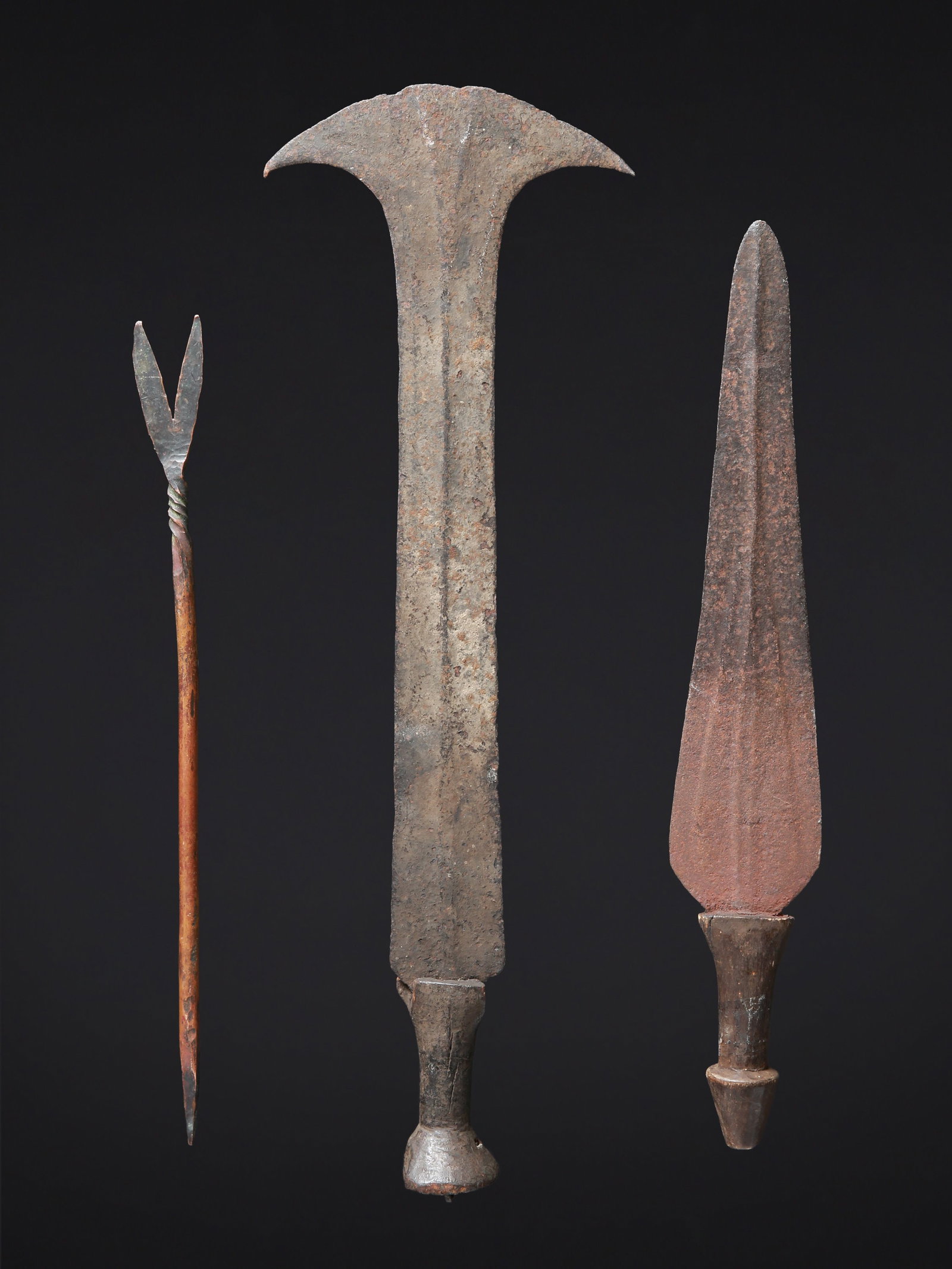 2 Ceremonial Knives and a Copper Currency: 2 Prunkmesser und ein Kupfergeld DR Kongo Ohne Sockel / without base Holz, Eisen, Kupfer. L 38,5 - 51 cm. Provenienz: Schweizer Privatsammlung, Zürich. Zeremonialwaffen zeichnen sich durch eine