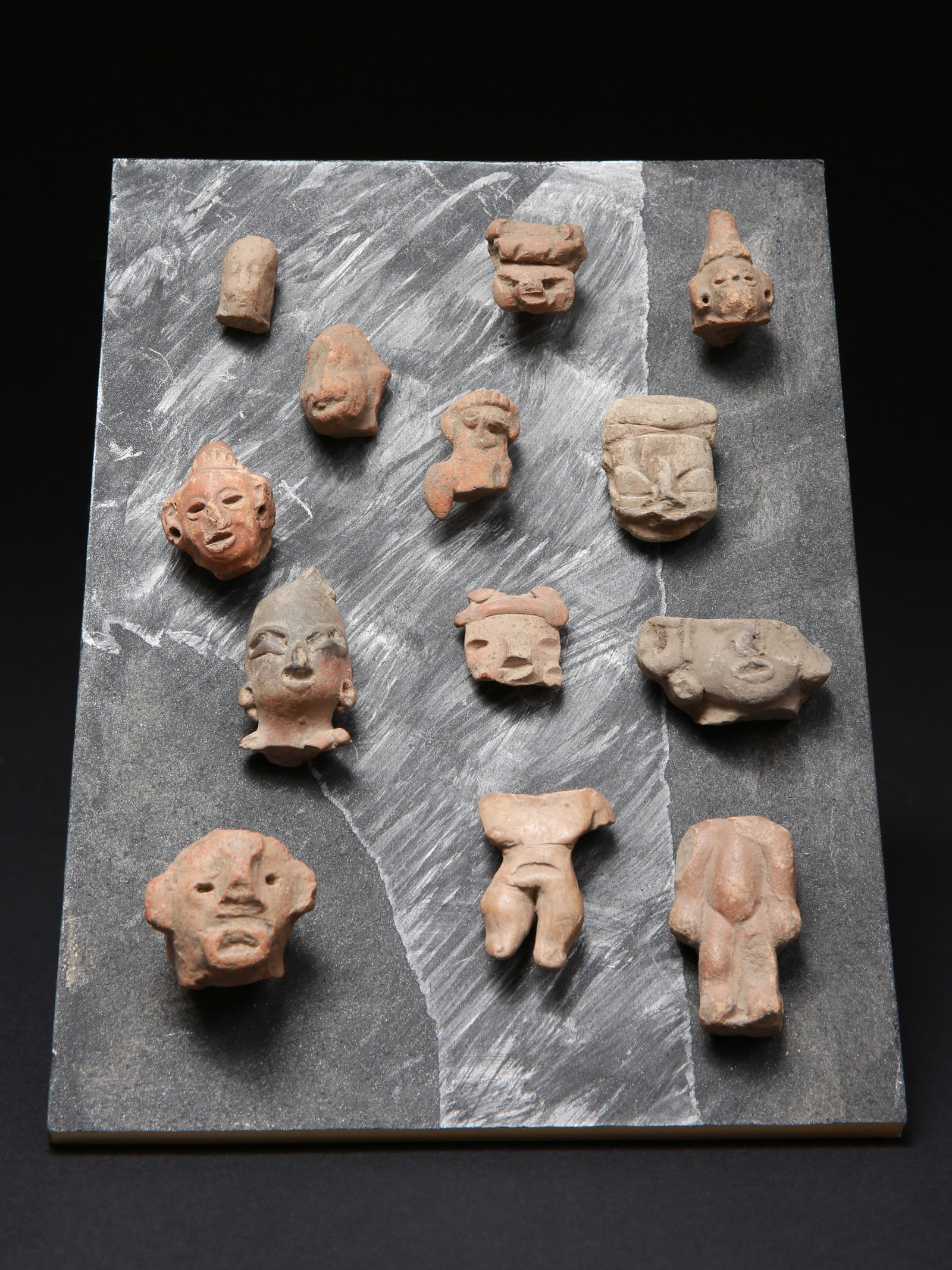 Lot consisting of thirteen figurative terracotta miniatures: Los bestehend aus dreizehn figurativen Terrakotta-Miniaturen Auf Holzbrett geleimt Terrakotta. H 2 - 5 cm. Provenienz: Schweizer Privatsammlung, Bern. CHF 150 / 300