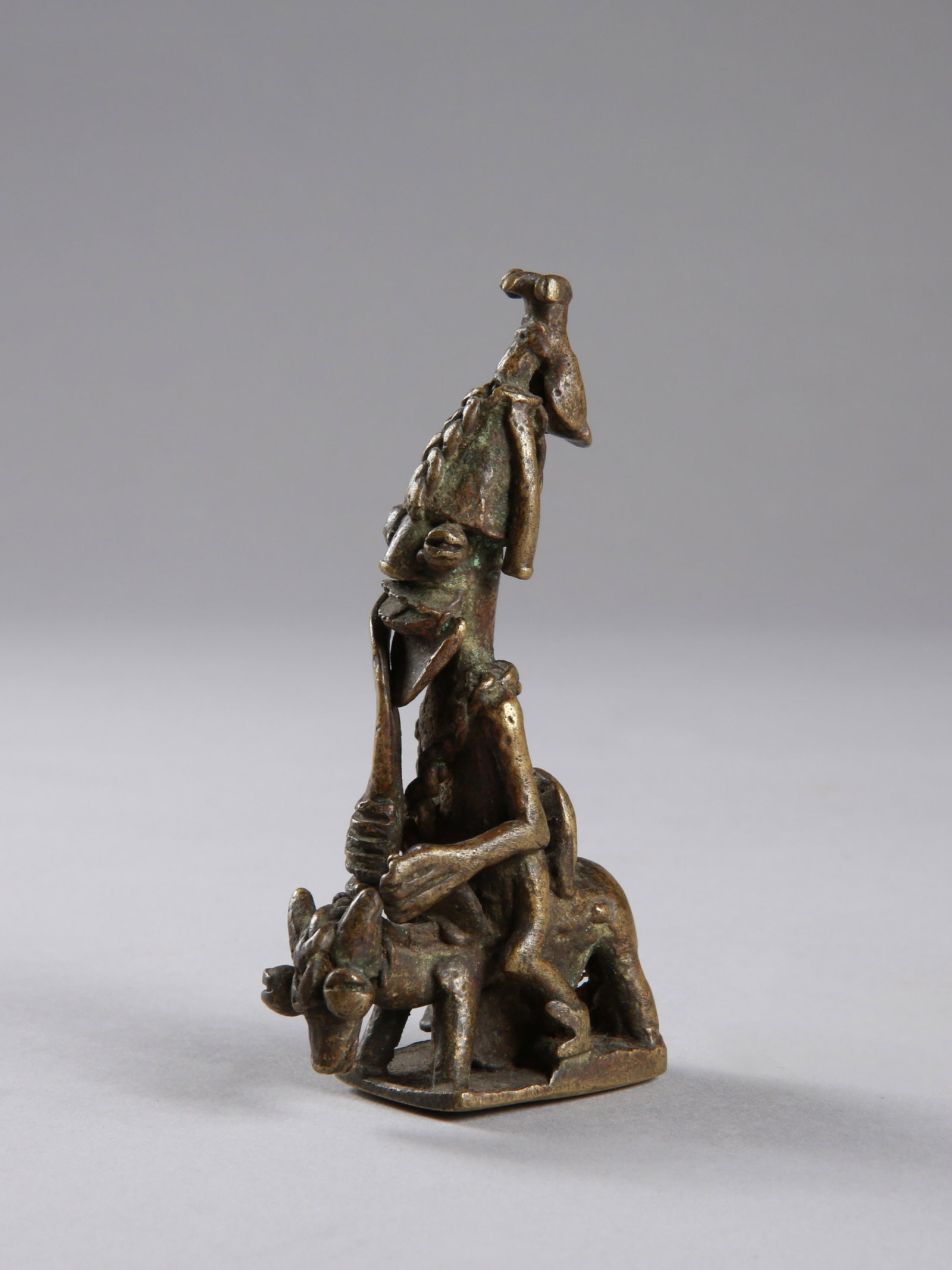 A Yoruba Horseback King (Upper Part of a Ceremonial Staff): Reitender König (Oberteil eines Zeremonialstabes) Yoruba. Nigeria Ohne Sockel / without base Gelbguss. H 10 cm. Provenienz: Galerie Walu, Zürich (vor 1995). Darstellung eines reitenden K