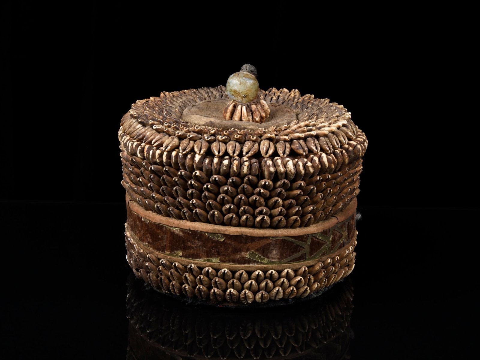 A Yoruba Altar Container, “ilé-orí” (House of the Head): Altarobjekt, "ilé-orí" (Haus des Kopfes) Yoruba. Nigeria Ohne Sockel / without base Holzstreifen, Leder, Stoff, Kaurischnecken. H 19 cm. Ø 20 cm. Provenienz: - Galerie Walu, Zürich