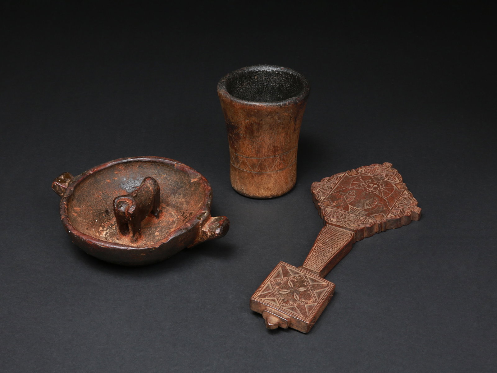 An Amhara Hand Cross, an Aymara Chicha bowl, and Chicha Cup: Handkreuz, Chicha-Schale und -Becher Äthiopien / zentraler Andenraum Ohne Sockel / without base Holz. H 1 - 14 cm. L 7,5 - 34 cm. Provenienz: Schweizer Privatsammlung, Zürich. Vor 1970 in