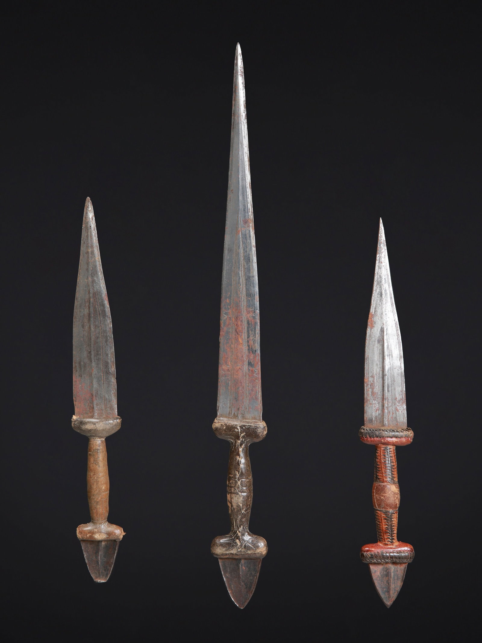3 Tuareg Daggers: 3 Dolche Tuareg. Sahelzone Ohne Sockel / without base Holz, Eisen, Leder. L 27,5 - 40 cm. Provenienz: Laurence und Jean-Pierre Boillod (1929-2007), Areuse. Zeremonialwaffen zeichnen sich durch eine