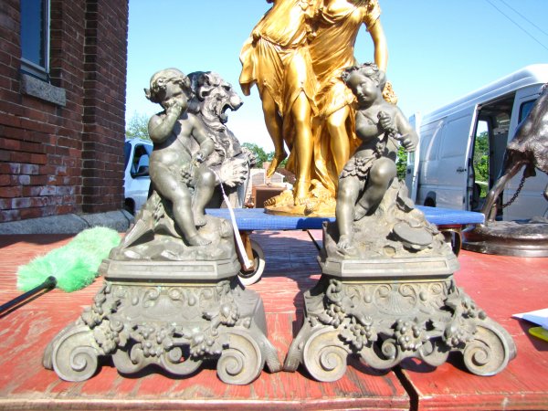 PR OF ANTIQUE CAST BRONZE CUPID CHENETS 3727: Ornate cast bronze cupid chenets on elaborate seashell and grape garland base. Dimensions: 14"H x 11"W x 7"D Age: 1880 Material: Bronze