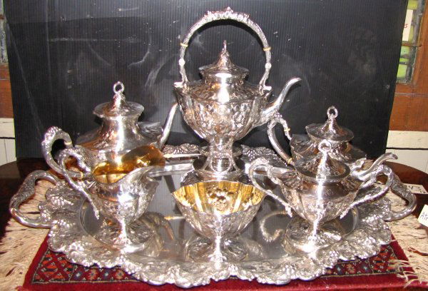 299 TROY OZ ANTIQUE STERLING SILVER TEA SET 3743: Seven piece antique sterling silver tea set with grapes, vines and leaf pattern. Marked Sterling and hallmarked with a Fleur de Lis within a shield (could not find the name of this makers mark). Dimen
