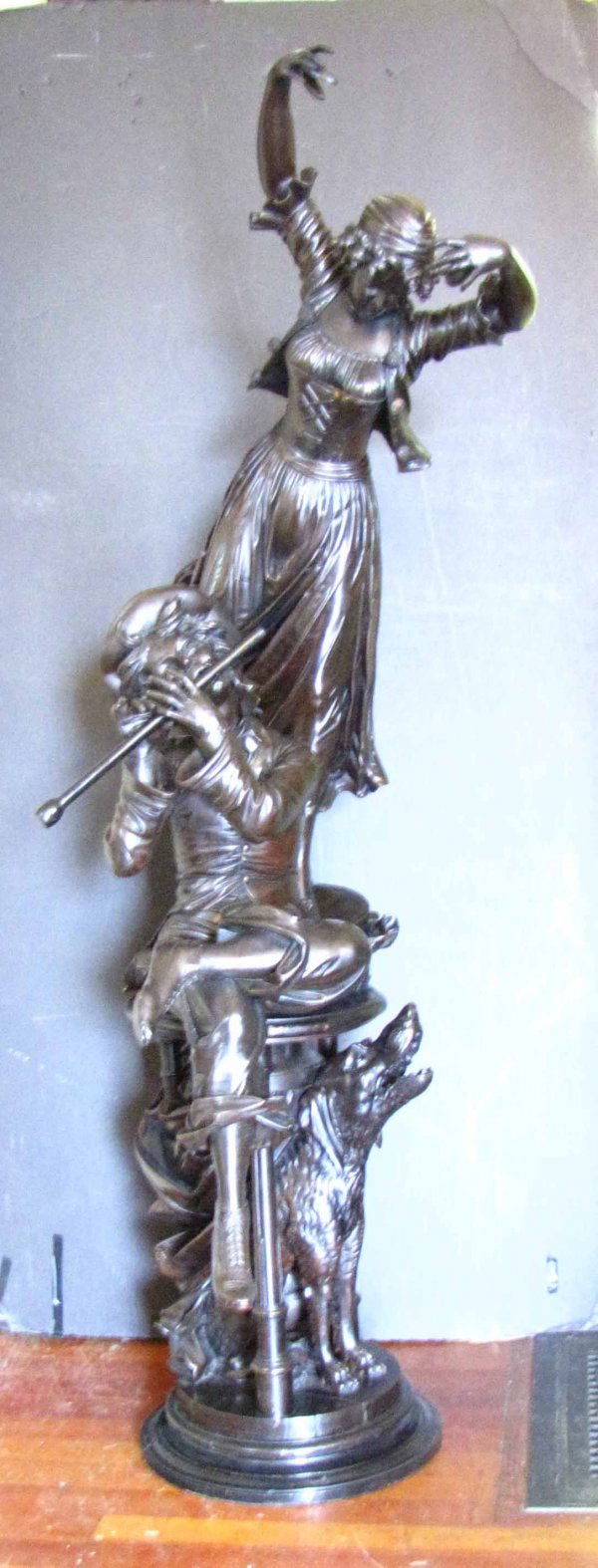 CARVED WOOD STATUE OF LADY WITH BOY AND DOG 1602: Exceptional carved wood statue of lady playing hand cymbals, boy with legs folded playing flute, and dog howling under the table. Dimensions: 79"H x 32"W x 36"D. Age: 1880 Material: wood