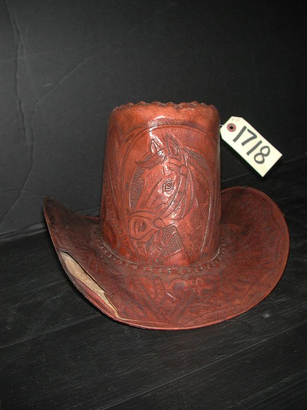 TALL TOOLED LEATHER COWBOY HAT & TIGER TOP (1725): Unusually tall tooled leather cowboy hat lifting on front lip with horse front & tiger top. Dimensions: 9"H x 12"W Age: 1950 Material: Leather