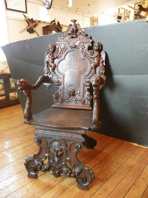 CARVED FANTASY ARM CHAIR EAGLE WGND CUPIDS ETC 4400: Outrageously carved fantasy arm chair with eagle crest flanked by winged cupids, North-wind face with garland, incised back rest and seat with griffin head hand rest….Awesome! 50"H x 25"W x 22.5'D.