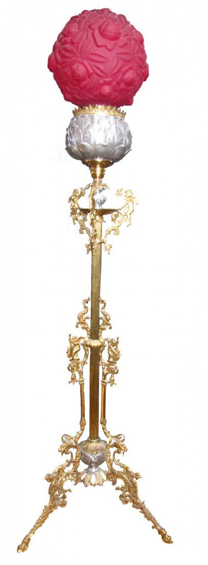 CAST BZ OIL FLOOR LAMP W/WINGED CHERUBS&SHADE 9915: Ornate cast bronze floor lamp with winged cherubs & blown-out red rose shade. Dimensions: 64"H x 19"Dia base Age: 1880 Material: Bronze & glass shade.