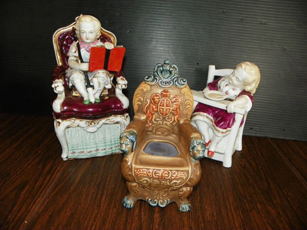 3 PORCELAIN HIGH CHAIRS 2 R LIDDED CONTAINERS 2325: Three porcelain chairs two are lidded containers with children in high chairs and one throne chair with lions and pin cushion or for finger wetting to count money. Dimensions: Assorted. Age: 1st quart