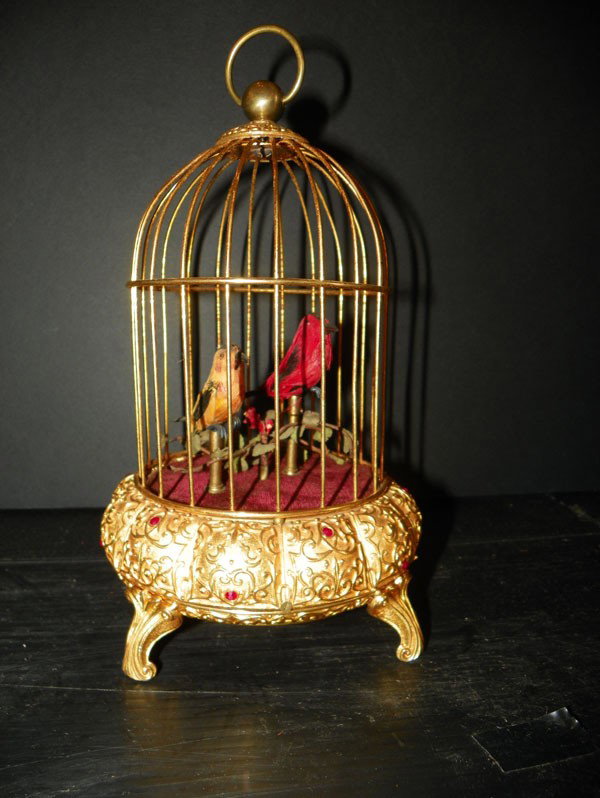 GOLD MECHANICAL SINGING BIRD CAGE W/ JEWELS 2316: Small gold Dore mechanical singing bird cage with red faceted jewel accents and two birds. Dimensions: 10.5"H x 6.5"Diameter Age: C 1880. Materials: Bird and Brass WE HAVE 3 GREAT BIRD CAGES, TWO OF W