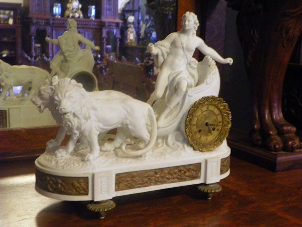 BISQUE CLOCK OF LIONS DRAWING CHARRIOT 2102: Intricate bisque clock of partial chariot drawn by two lions with cast bronze clock face and frieze in cuoid scenes. Dimensions: 15"H x 16"W x 5"D Age: C.1890 Material: Bisque