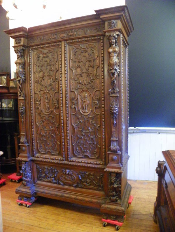 WRAP TAILED LADIES CARVED WALNUT WARDROBE 2032: Impressive two door carved walnut wardrobe with twisted tail lady side supports, lower lion supports holding book, knights in armor, winged Griffins, North wind face, dolphin garland and the list goes