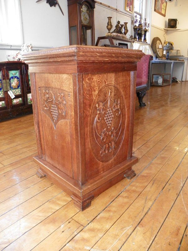 QUARTERED OAK PEDESTAL GRAPE MOTIF 4441: Well grained quartered carved oak square pedestal with grape and vine motif carvings on three sides. 28"H x 17.5"Sq. Age: C.1890. Material: oak