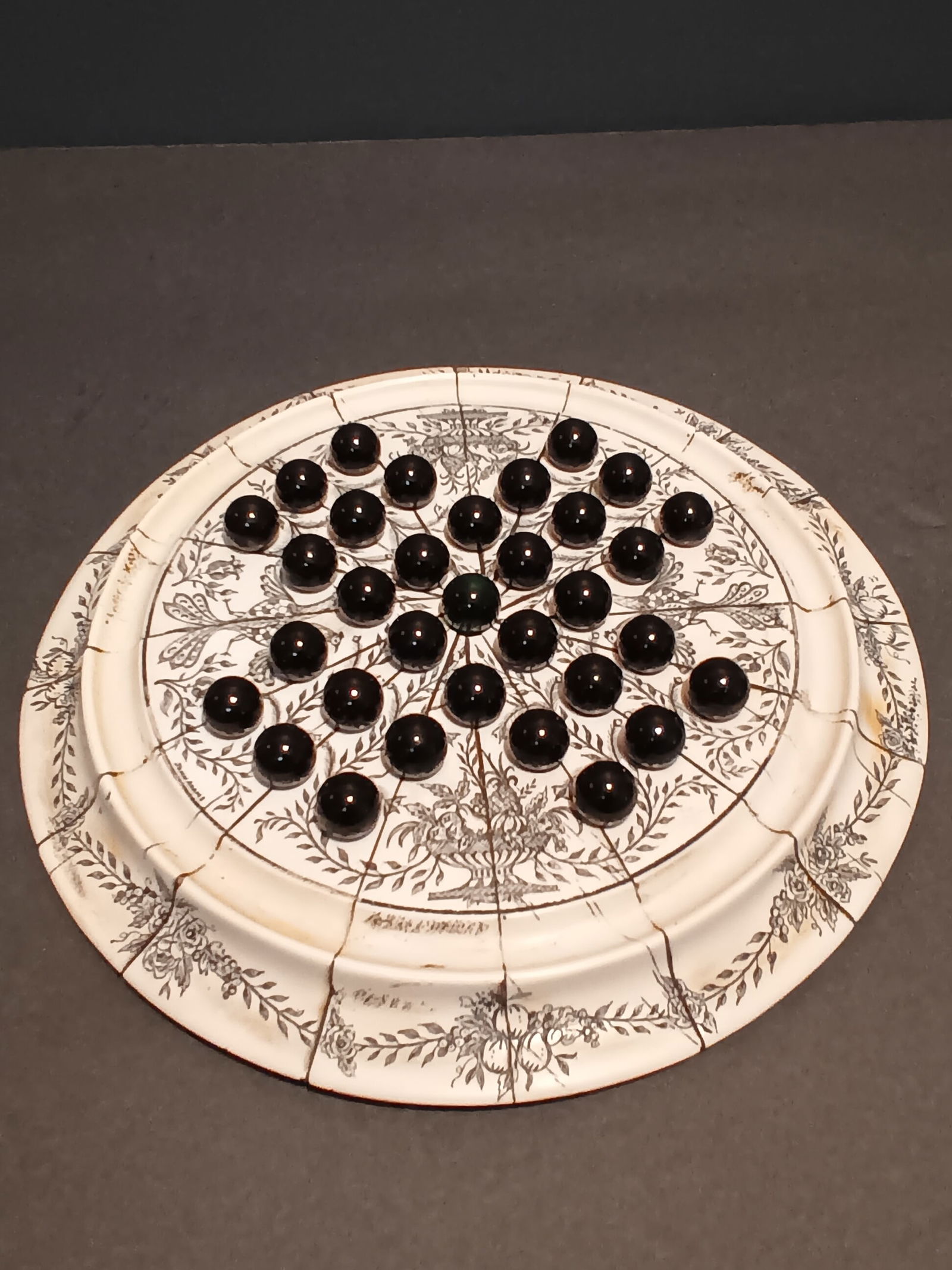 John Adams faux scrimshaw solitaire game board with marbles: John Adams faux scrimshaw solitaire game board with marbles. This is a reproduction and more than likely made of resin. From what I had seen online I believe these were made by 1 of the museums In the