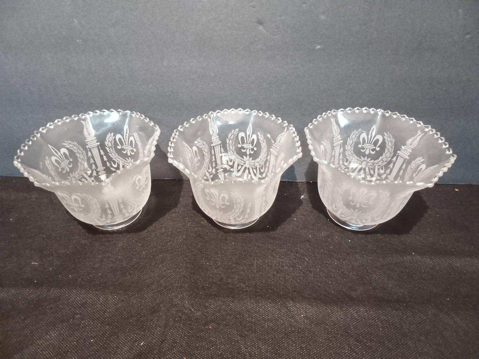 3 Early Electric shades Etched with Fleur-de-lis, Torch, Wreath & Ribbon Circa 1900, 2 1/4"F: 3 Early Electric shades Etched with Fleur-de-lis, Torch, Wreath & Ribbon in fine detail. These are Circa 1900 and with 2 1/4" Fitter lip. What is rare with these shades are nubs on the wavy edge and j