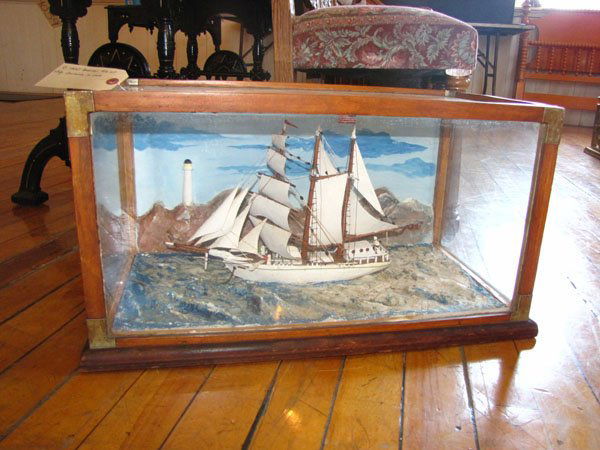 AMERICAN DIORAMA IN CASE OF SAIL BOAT ON SEA (4069): Turn of the century American Diorama in case of majestic Sail Boat on sea with near light house on rock ledge. Dimensions: 13"H x 26.5"W x 14.5"D Age: 1900 Material: Glass & wood
