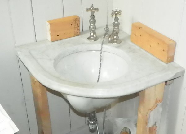 MARBLE CORNER SINK TOP W/ PORCELAIN BASIN 1511: Antique marble corner sink top with porcelain basin and 2 faucets. The sink comes with some of the pipes needed. There is a small crack in the marble at the left side faucet. The sink measures 20 1/4"