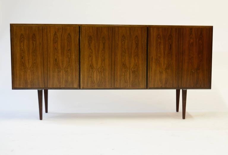 Gunni Omann Rosewood Credenza: A finely-grained rosewood Model 30 credenza by Danish Mid-Century designer Gunni Omann for Omann Jun. Upper drawer and adjustable shelf in the left compartment. Double adjustable shelves in the center