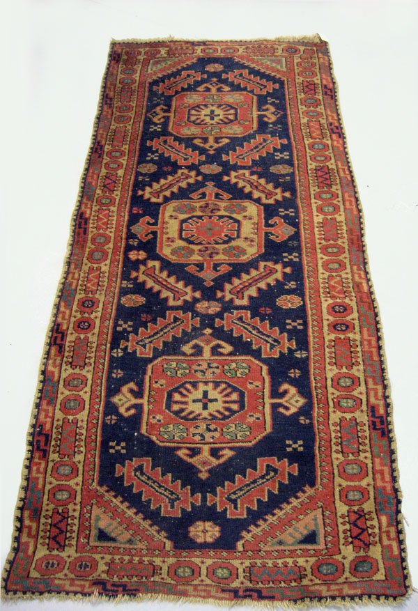Oriental rug. Caucasian runner. Three geometric me: Oriental rug. Caucasian runner. Three geometric medallions on a blue ground. Note border end loss. Appropriate age wear. 78'' x 33 1/2''. $100-150