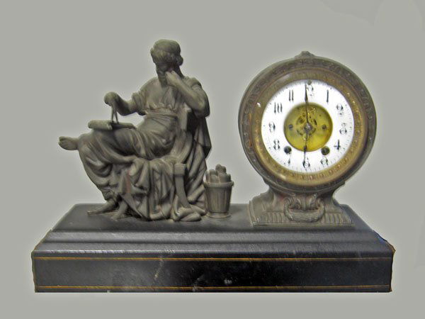Spelter figural clock with a seated Greco Roman ma: Spelter figural clock with a seated Greco Roman man with calliper and scrolls resting on a slate base. Old repair to slate and worn finish. Age wear. 12 1/2''h x 18''l x 6 3/4''w. $150-200