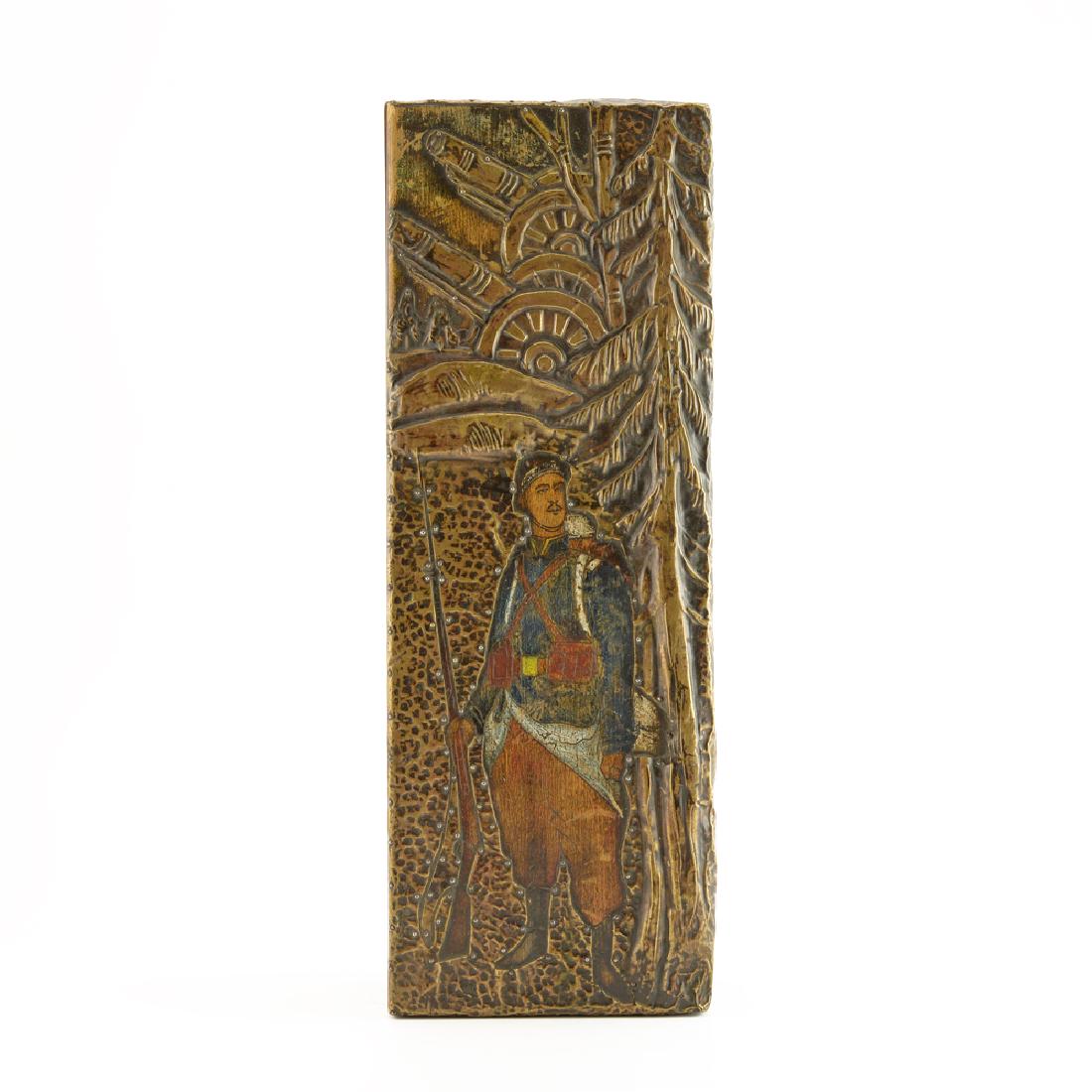 World War I: A Russian folk art carved wood box: The rectangular wood box with hinged lid painted with a soldier standing with his rifle, reserved within an applied bronze plate chased with cannons in a forest, the metal on the sides of the lid with