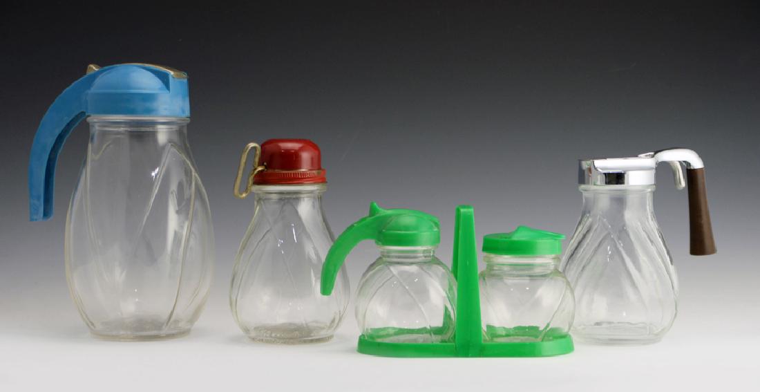 5 Zeisel Federal Tool Pitchers: Eva Zeisel, a group of five Glass Pitchers, all with plastic and/or metal fittings for serving juice, syrup, or other sauces, a Cheese Grater with a red metal cover for grating cheese, the smallest fo