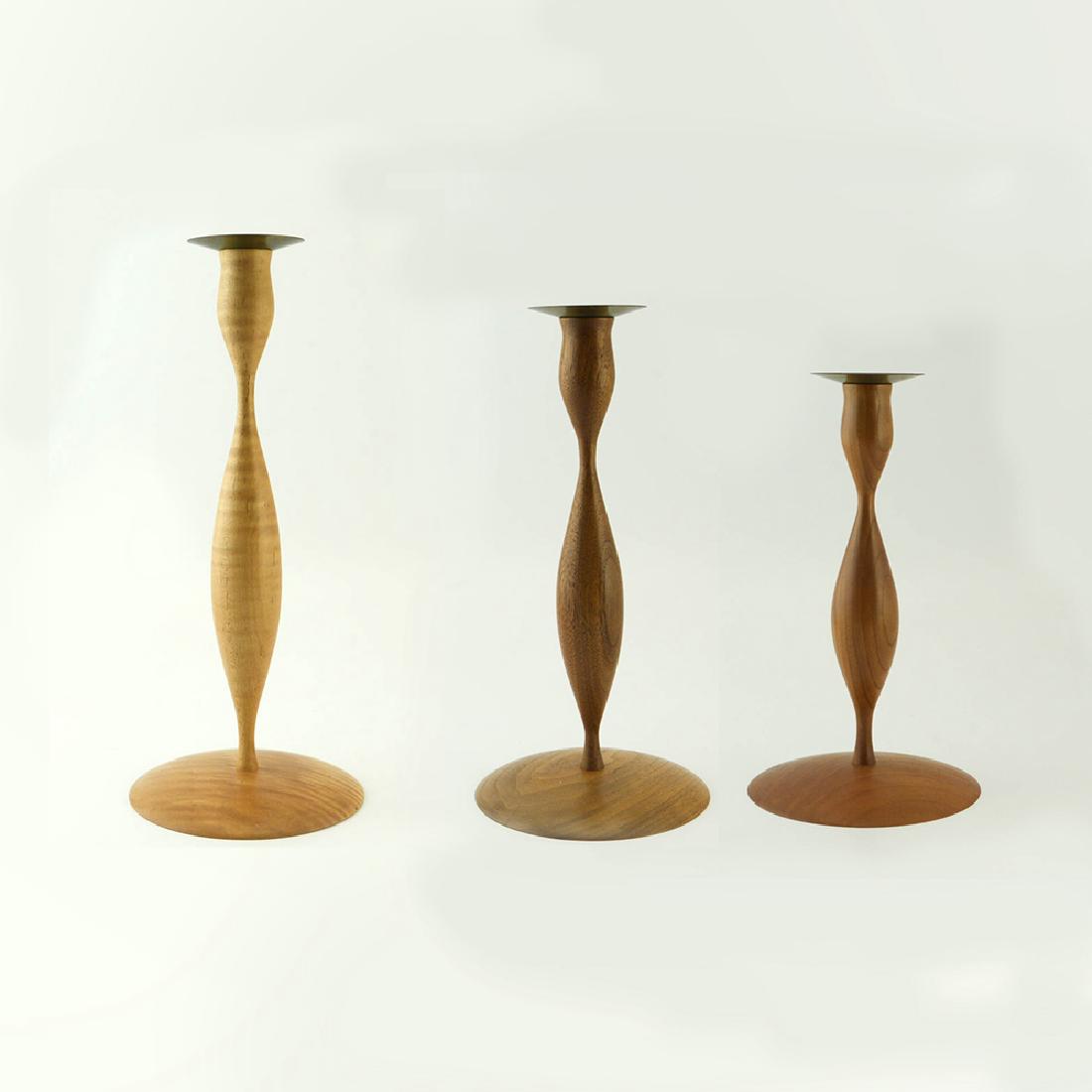 3 Zeisel Turned Wood Candlesticks: Eva Zeisel, a group of three rare turned wood Candlesticks with brass nozzle, RB Universal Woodworks for Orange Chicken, 1997. The underside with burned marks RB Universal Woodworks and Eva Zeisel. A