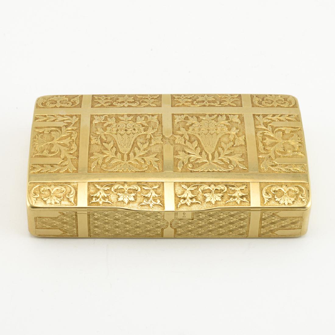 A Russian circa 1820 Gold Floral Snuffbox: A Russian gold box, Moscow, circa 1820. The case formed as a traveling trunk with arched lid, chased and engraved to simulate leather straps with floral ornament between. Struck with Moscow and 56 gol