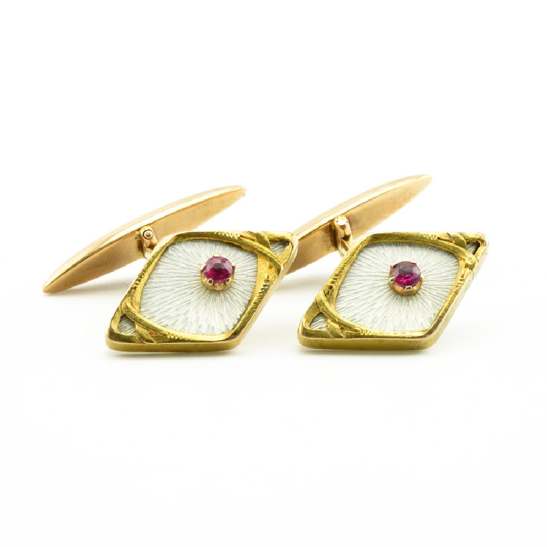 A pair of Russian Art Nouveau gold enamel, ruby: A pair of Russian gold, translucent enamel, and ruby cufflinks, St. Petersburg, 1908-1917. In Art Nouveau taste, the links of navette form, enamelled translucent white over a hatched sunburst ground a