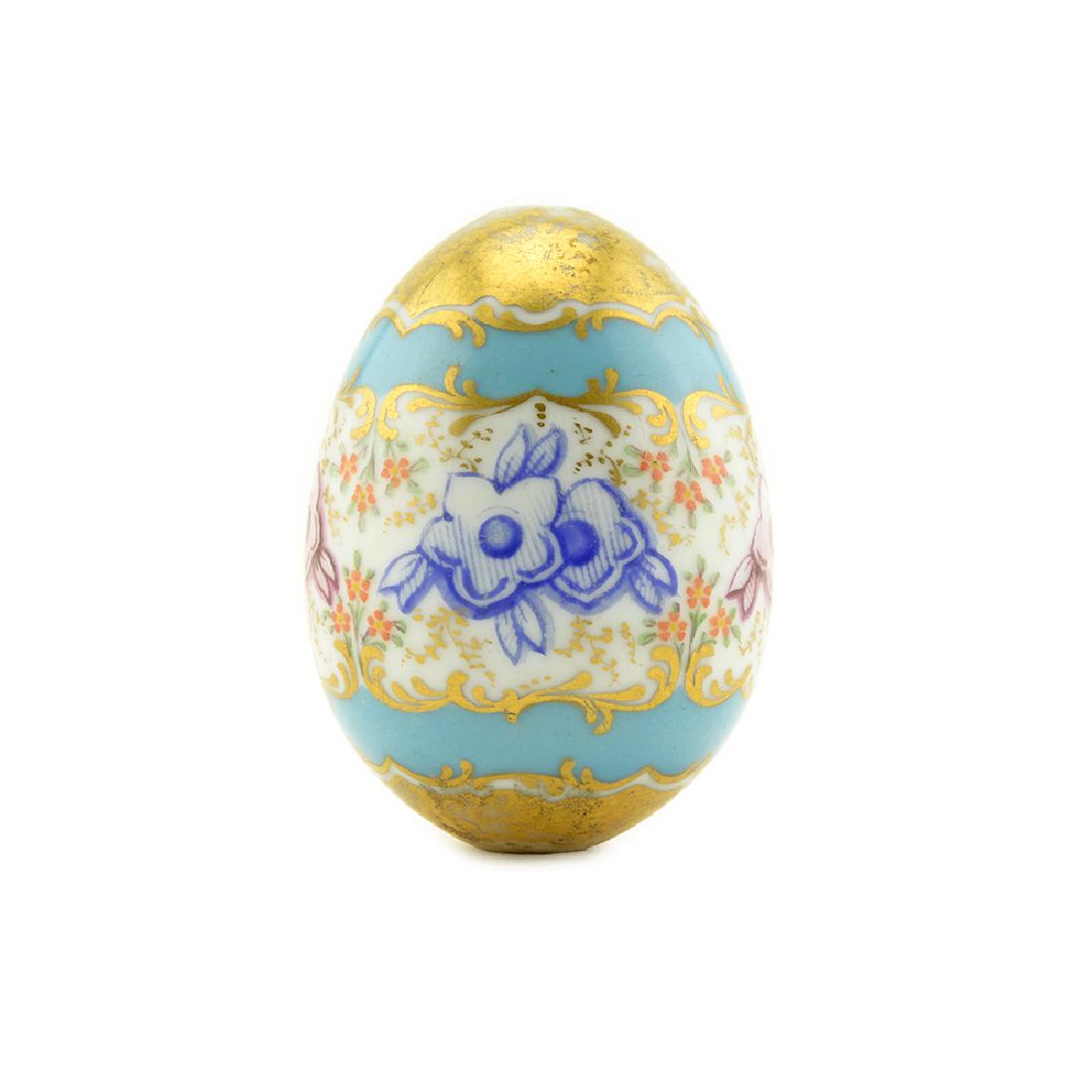 A RUSSIAN PORCELAIN EASTER EGG IN ROCOCO STYLE: A Russian porcelain Easter egg, circa 1860. In Rococo Revival taste, decorated with brightly-colored blossoms between scrolling gilt borders reserved against a robin’s egg blue ground, the upper and