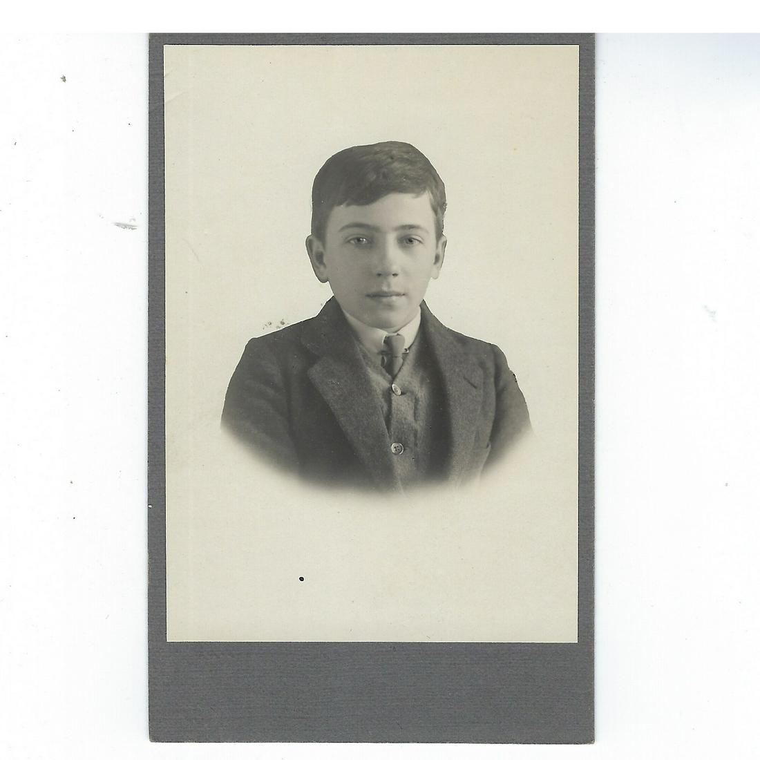 Photo of a young boy in suit: Photo of a young boy in suit, glued down on gray card Dimensions: 4 5/8 x 3 in.