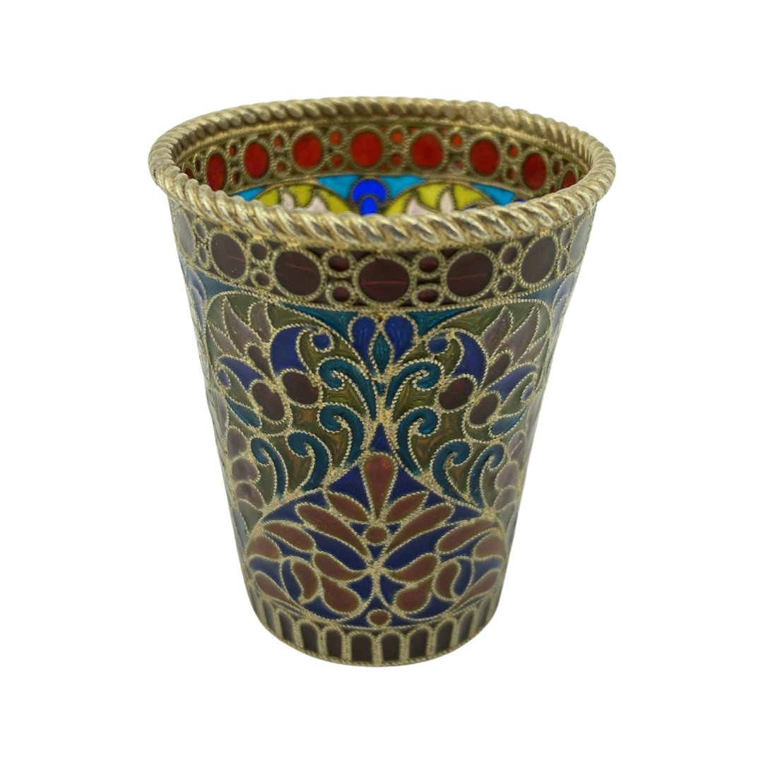 An Ovchinnikov Plique Enamel Beaker: A Russian silver gilt andplique-a-jour enamel toasting beaker or shot glass, Ovchinnikov, Moscow, 1899-1908. The small, tapering cylindrical beaker enameled in a pattern of scrolling, stylized flowers