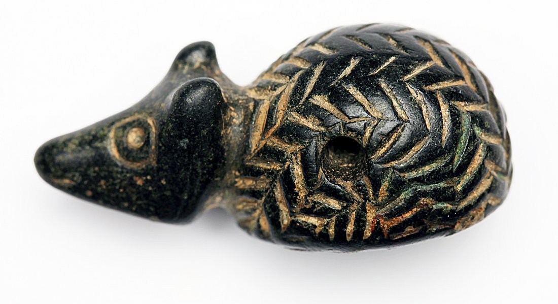 A Stone Amulet of a Hedgehog with Intaglio: Egypt; c. 1st century BC The corpulent fellow with houndstooth pattern spines. Underneath, an intaglio of a camel. Dimensions 1 7/16 (3.7 cm) Provenance: Provenance: The John J. Slocum Collection