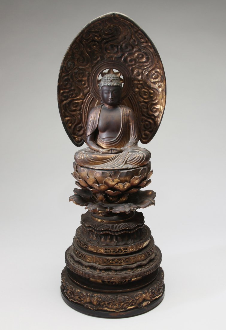 A Japanese Gilt Wood Seated Buddha: Japan; Edo Period, c. 18th century Seated on lotus pad, a deeply carved mandorla behind. The base is particularly well carved and very intricate. Very high quality. Dimensions 23" (58.5cm) high.