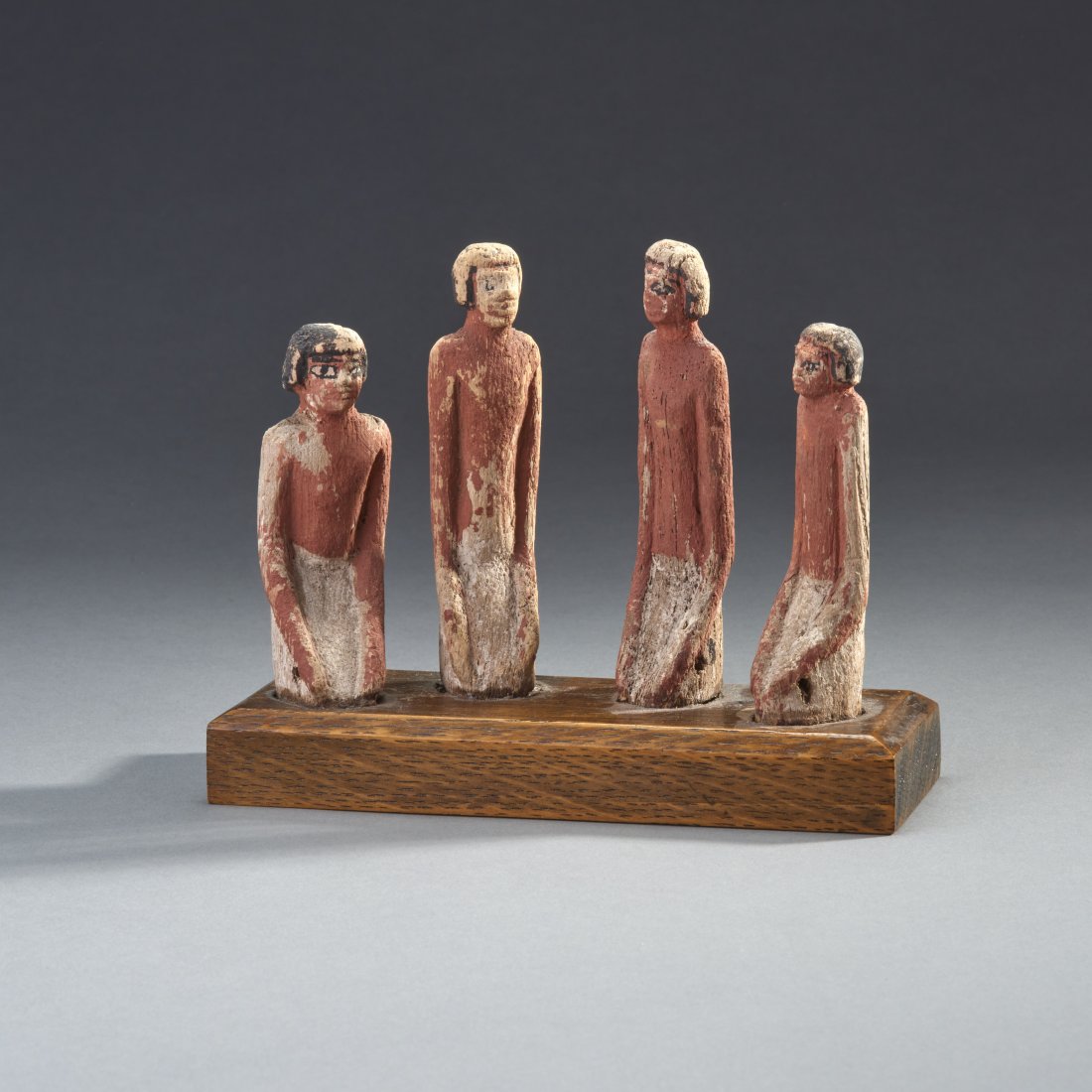 Four Egyptian Wooden Boatmen Ex Royal Athena: Ancient Egypt, 11th-12th Dynasty, ca. 2040-1782 BC. Four ancient wooden boatmen. The four kneeling servants with red skin, black wigs, and white kilts. Custom base. Purchased at Royal Athena,NYC 12/1/